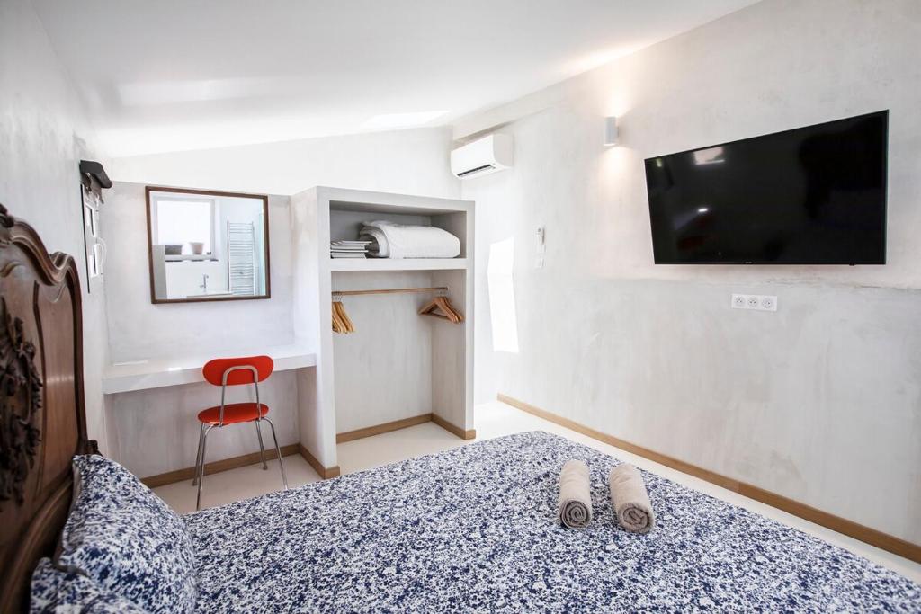 - une chambre avec un lit, une télévision et une chaise rouge dans l'établissement Le cabanon de Samatan, à Marseille