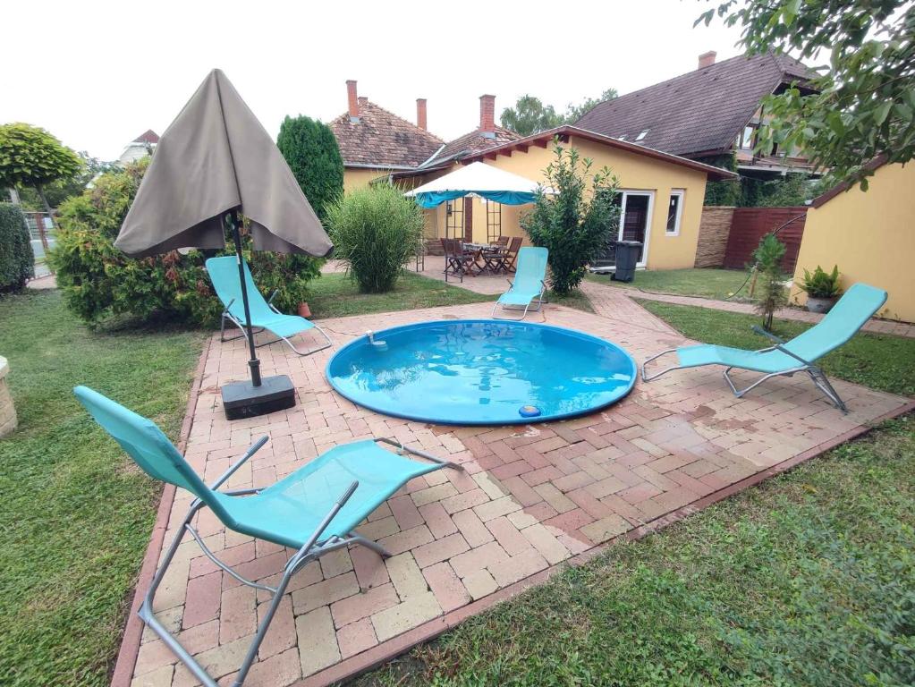 a pool with chairs and an umbrella in a yard at Holiday home in Siofok - Balaton 45810 in Siófok