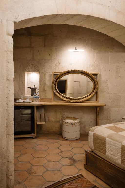 a bathroom with a mirror and a bed in a room at Cappadocia Cave Suites Adult Only in Goreme