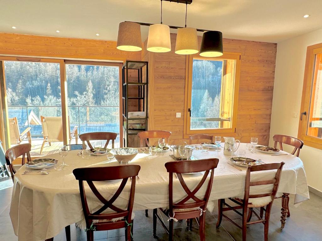 une salle à manger avec une table et des chaises blanches dans l'établissement Jardin des Eduits Serre Chevalier Chantemerle, à Saint-Chaffrey
