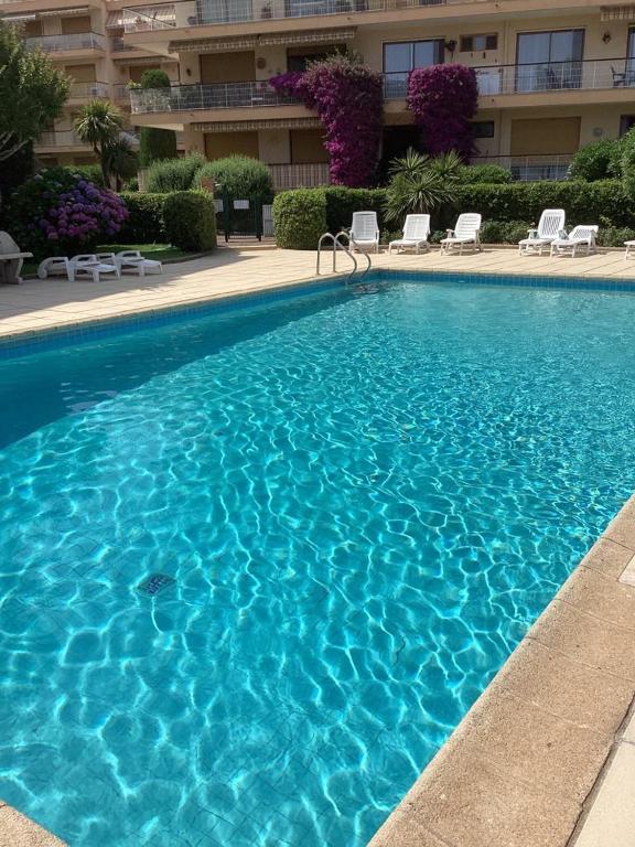 une grande piscine bleue avec des chaises et un bâtiment dans l'établissement Belle résidence arborée, Appart climatisé, piscine, à 500m de la mer, à Sainte-Maxime