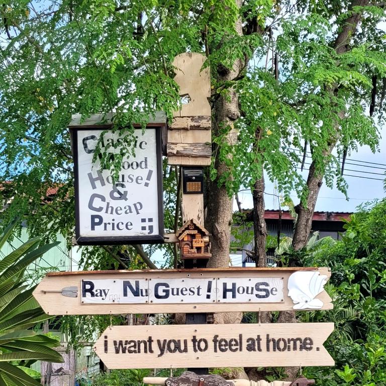 a sign hanging from a tree with some signs at Ray Nu Guest House in Phra Nakhon Si Ayutthaya