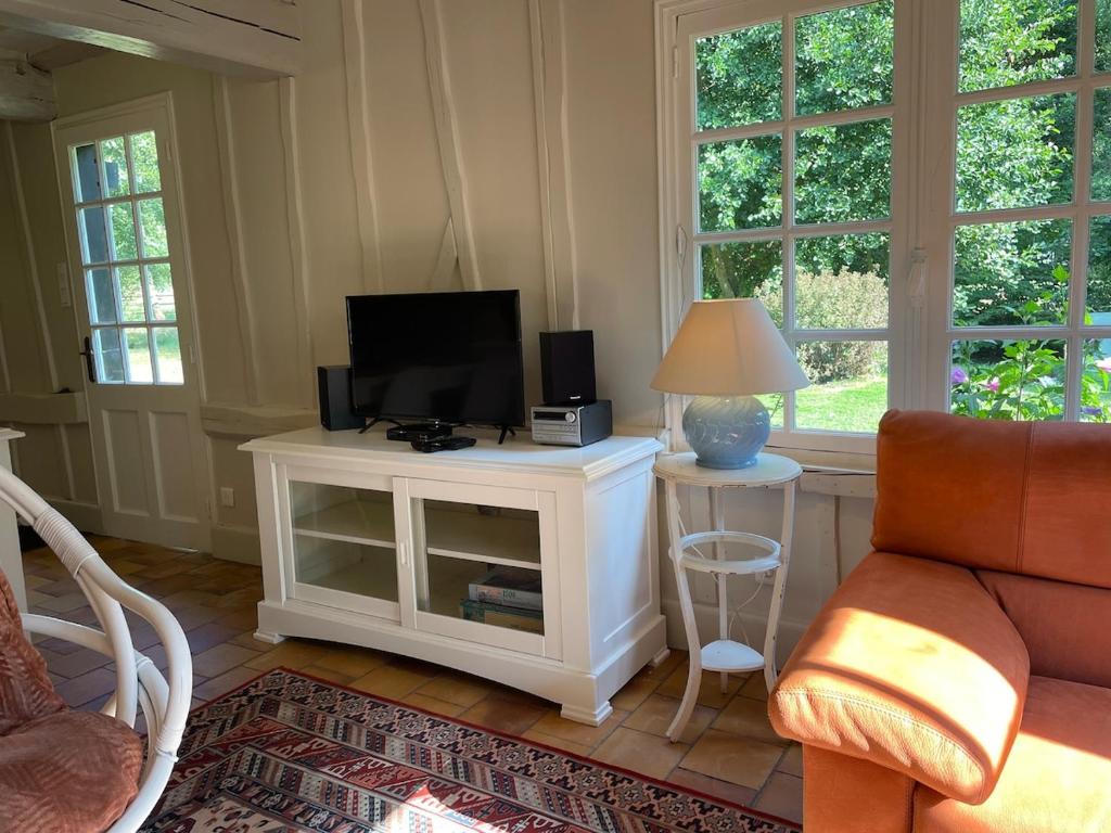 un salon avec une télévision sur un meuble blanc dans l'établissement LA SELLERIE Charmante maison de campagne au milieu d'une ile, à Canehan