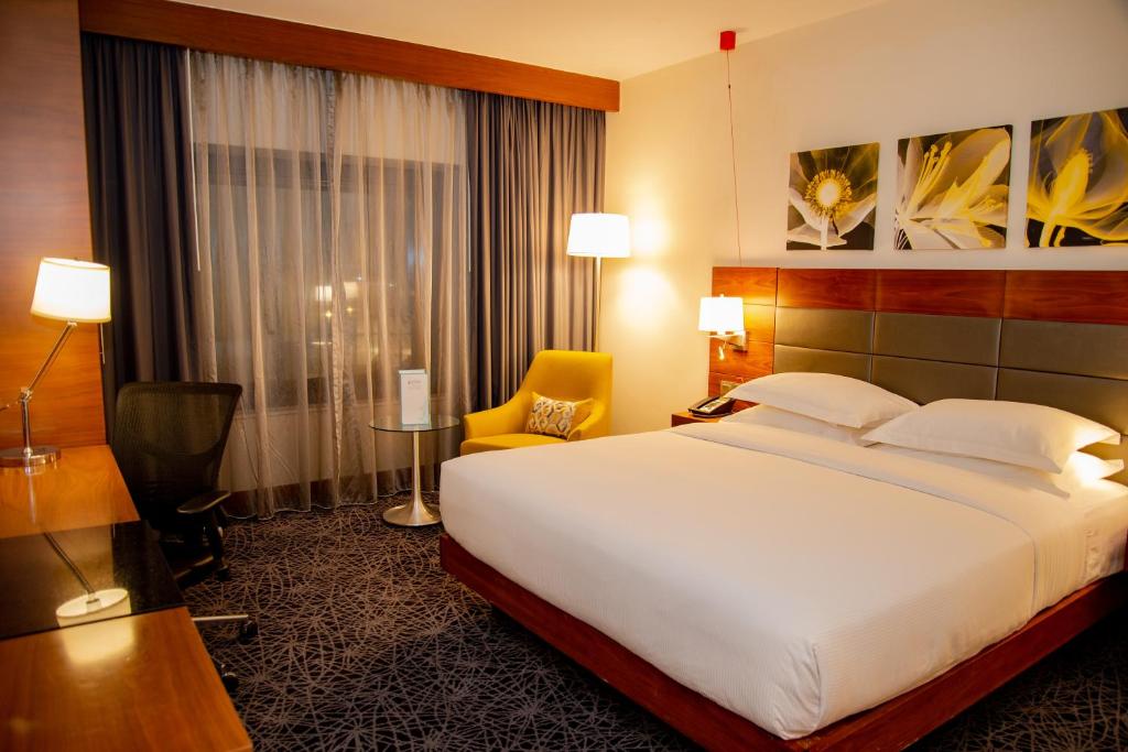 a hotel room with a large bed and a chair at Hilton Garden Inn Nairobi Airport in Nairobi