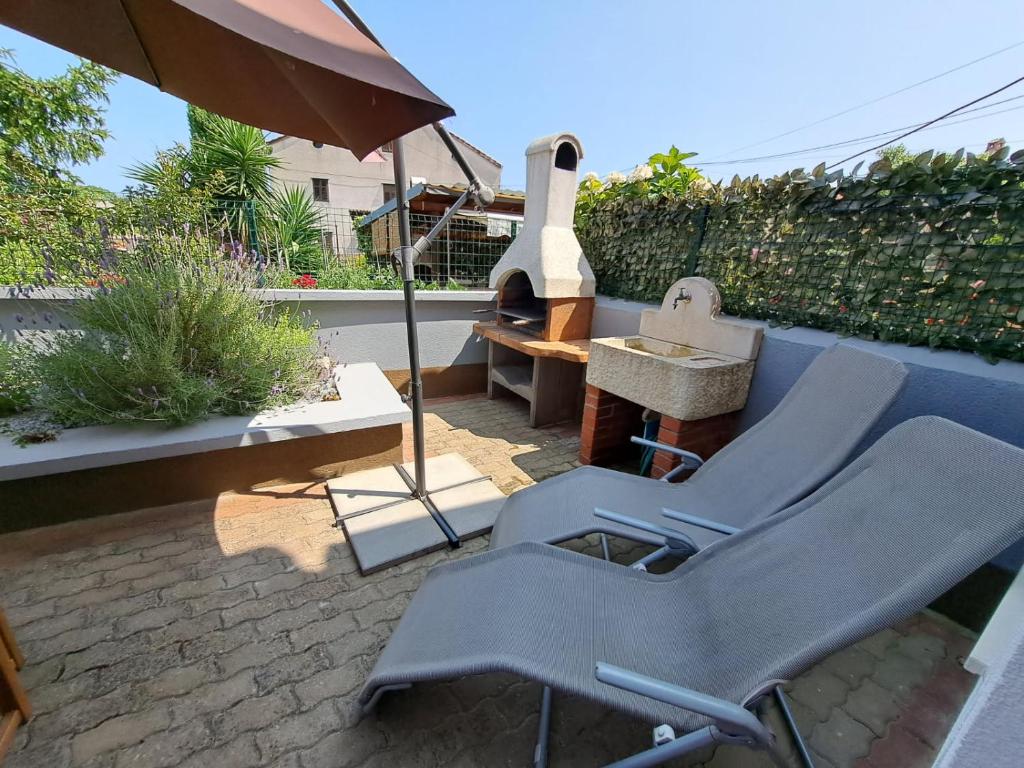 a patio with a couple of chairs and an umbrella at Federica A2+1 in Veli Lošinj