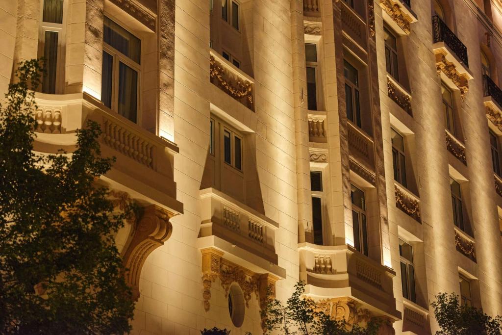 a tall building with lights on the side of it at The Palace, a Luxury Collection Hotel, Madrid in Madrid