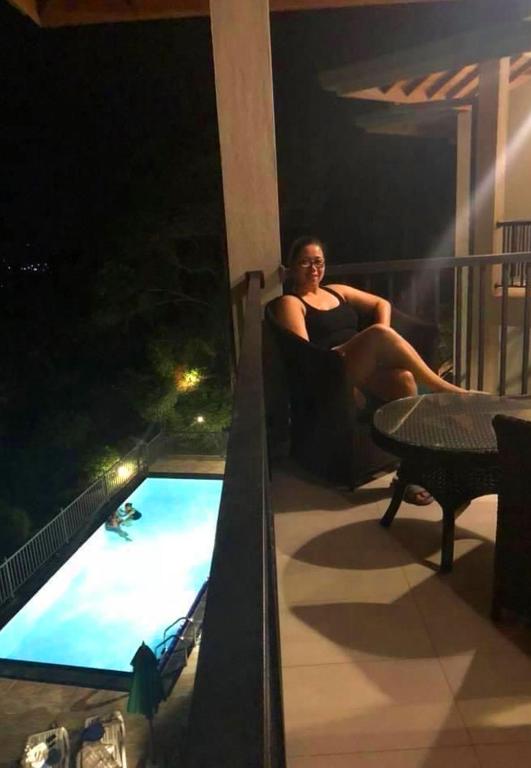 a woman sitting on a balcony next to a swimming pool at Grand Hills kandy in Kandy