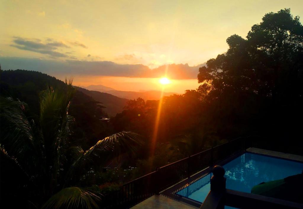 a person standing next to a swimming pool at sunset at Grand Hills kandy in Kandy
