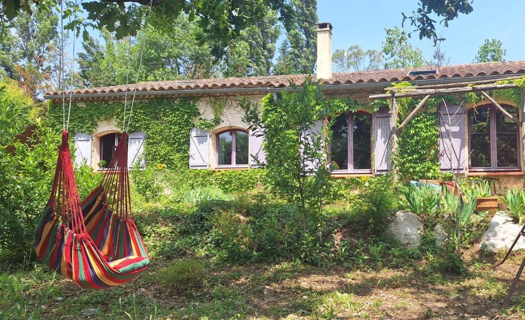 une maison avec un hamac en face de celle-ci dans l'établissement Gîte à la ferme, à Montolieu