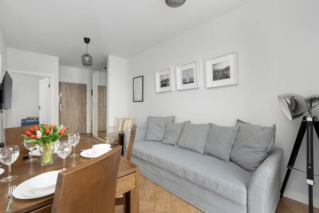 a living room with a gray couch and a table at Rewal Cozy Apartment with Parking, Gym, Spa & Pool close to the Beach by Noclegi Renters in Rewal