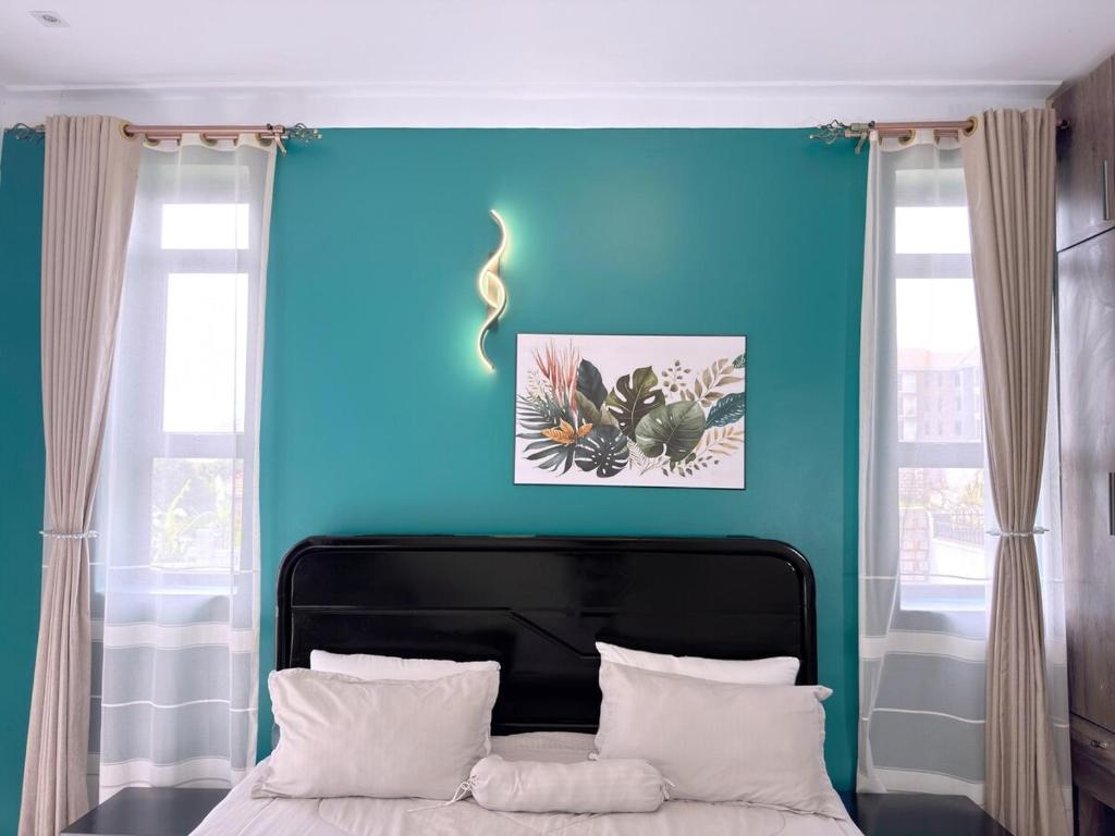 a bedroom with a blue wall and a bed with white pillows at Arana Royal Homes in Kampala