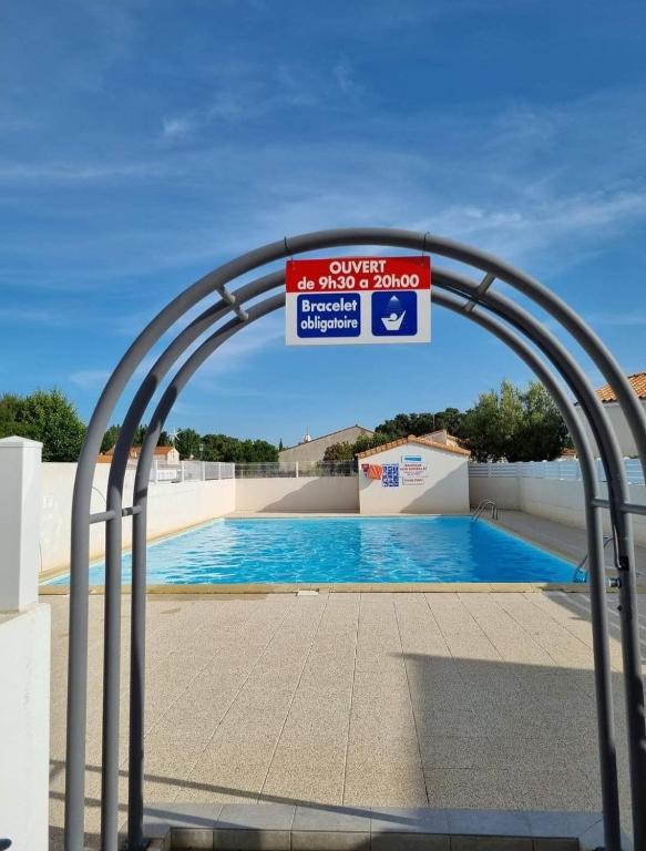 une piscine avec un portail avec un panneau dessus dans l'établissement maison dans résidence piscine juillet et août, à La Tranche-sur-Mer