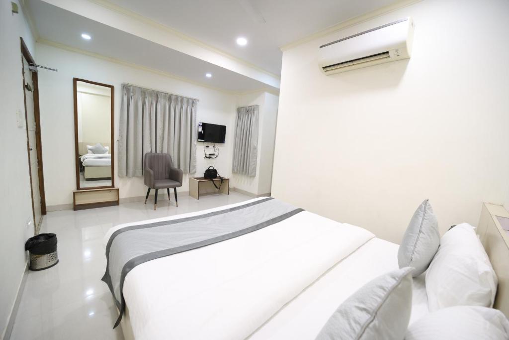 a white bedroom with a bed and a chair at Hari Haran Prestige in Varanasi