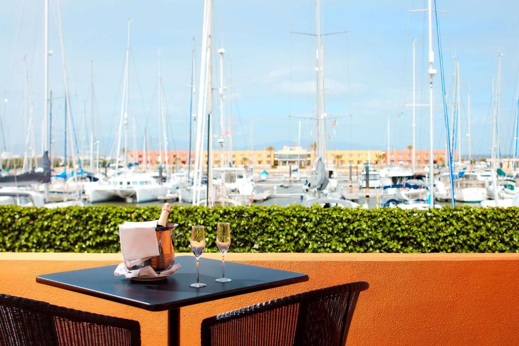 a table with two wine glasses and a laptop on it at NH Marina Portimao Resort in Portimão