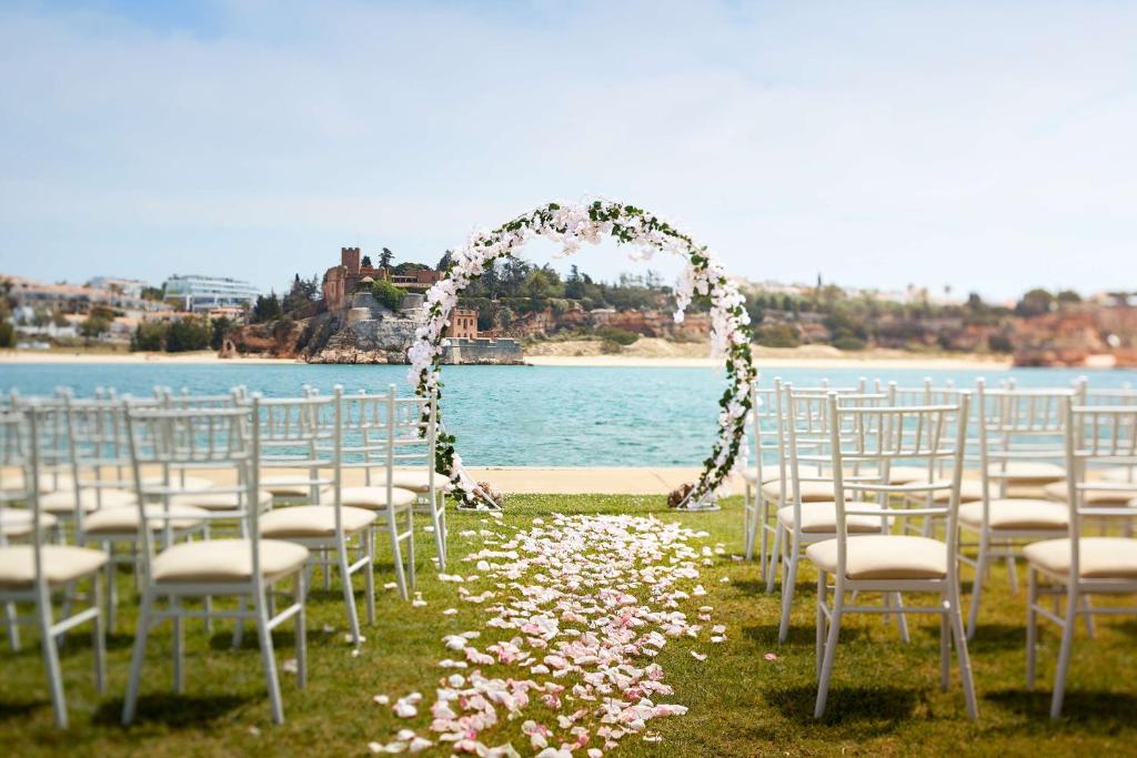a wedding arch with chairs and flowers on the beach at NH Marina Portimao Resort in Portimão