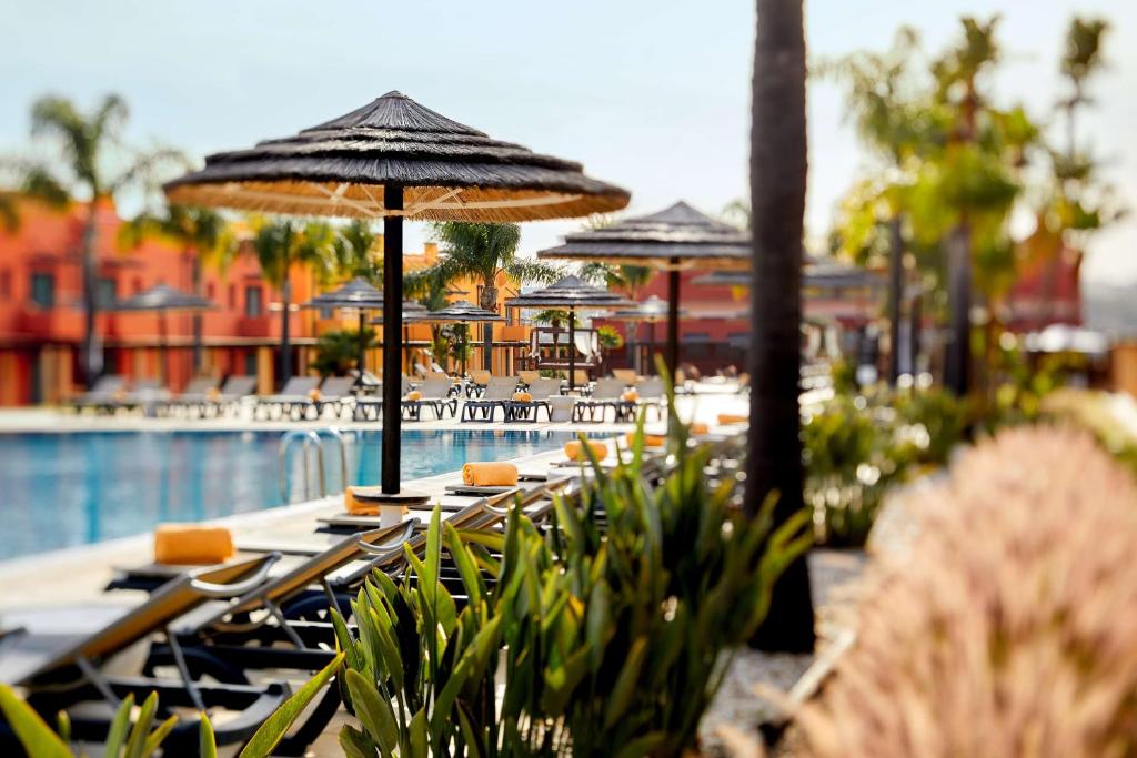 a group of tables with umbrellas next to a pool at NH Marina Portimao Resort in Portimão