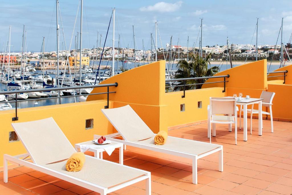 a balcony with tables and chairs and a view of a harbor at NH Marina Portimao Resort in Portimão