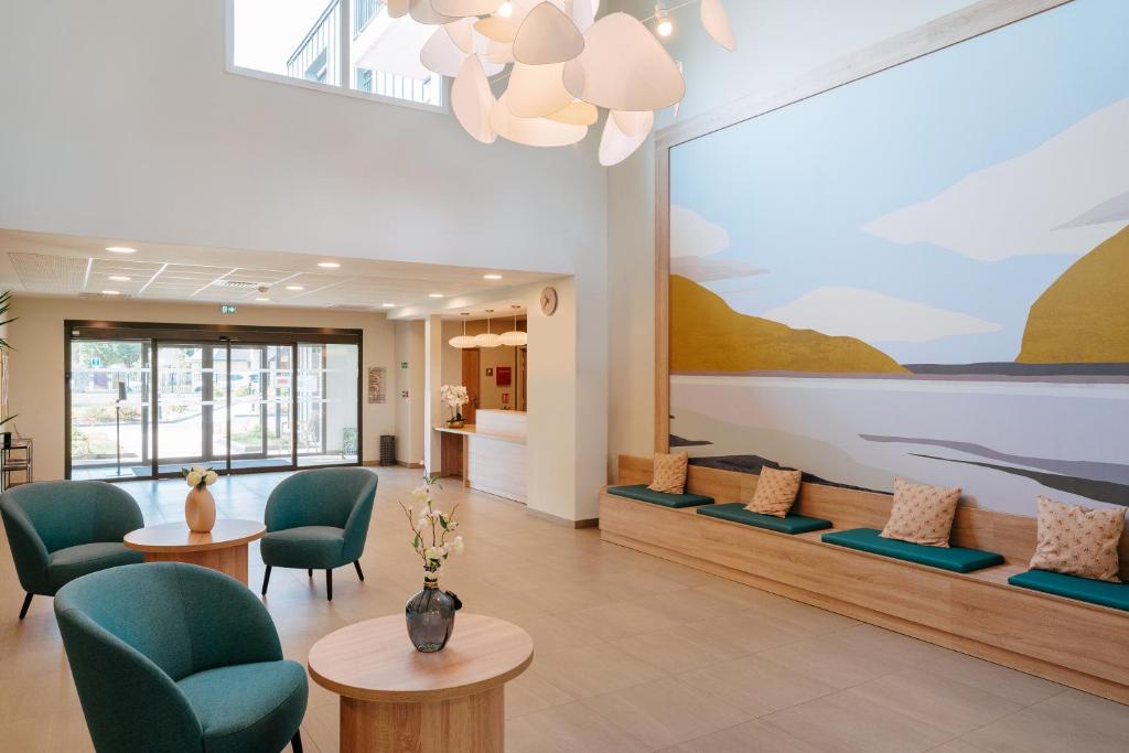 une salle d'attente avec des chaises vertes et un grand tableau sur le mur dans l'établissement Zenitude Hôtel-Résidences Ploërmel, à Ploërmel