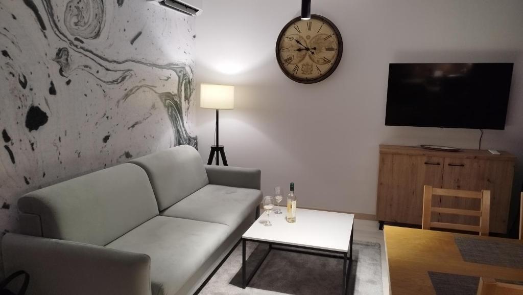 a living room with a couch and a clock on the wall at Wind Rose Montenegro in Igalo