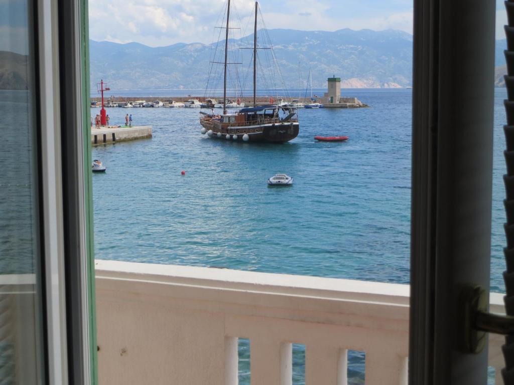 a view of a boat in the water from a window at Apartment Palada in Baška