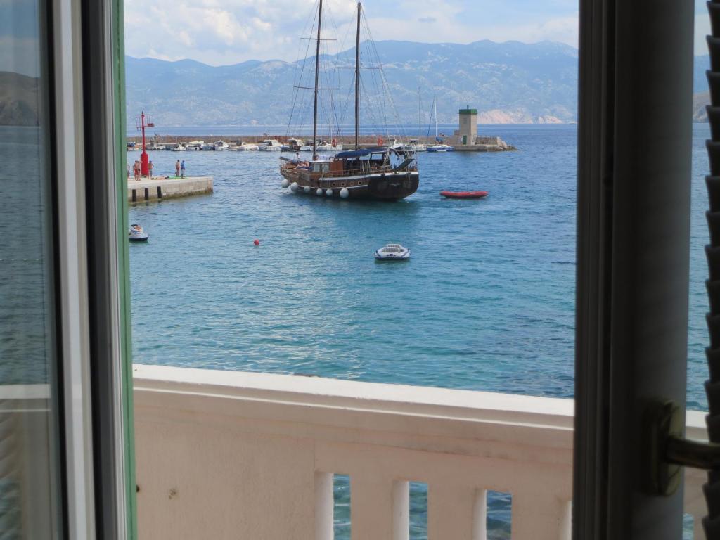 una ventana con vistas a un barco en el agua en Apartment Palada, en Baška