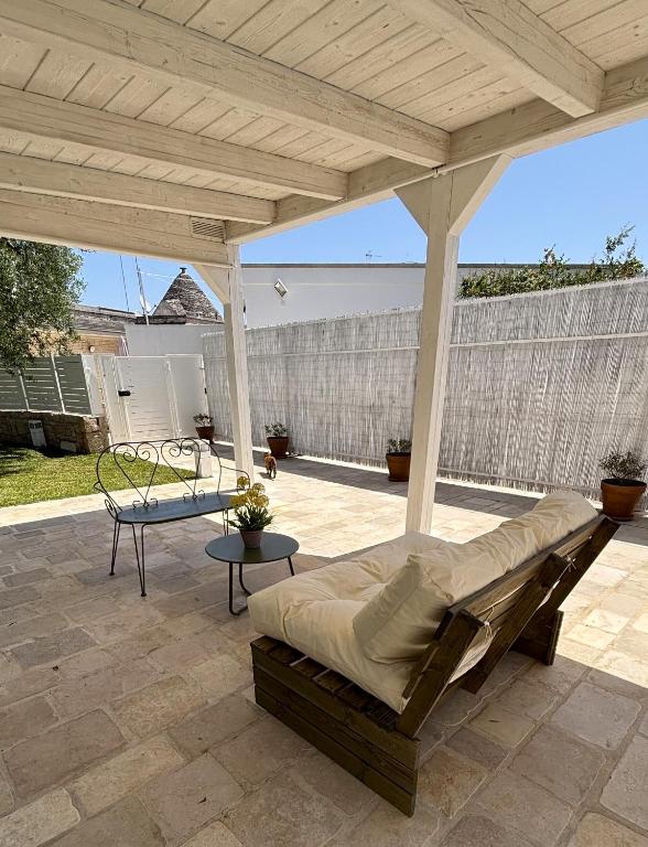 un patio couvert avec un lit et une table dans l'établissement La Cummersa Trulli Holiday, à Alberobello