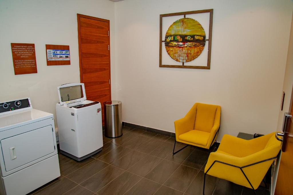 a waiting room with a refrigerator and a yellow chair at Hilton Garden Inn Nairobi Airport in Nairobi