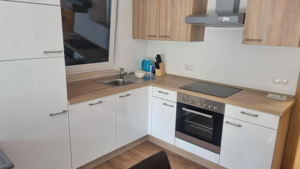 a kitchen with white cabinets and a sink at Apartman Mara in Malinska