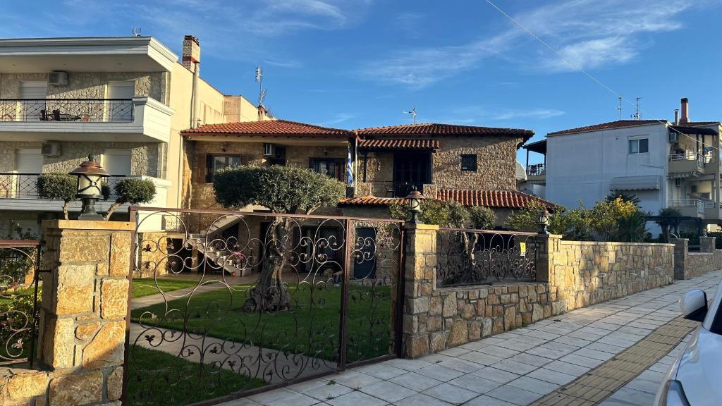 a house with a stone fence and a gate at Apartment Greek Mansion in Nea Moudania