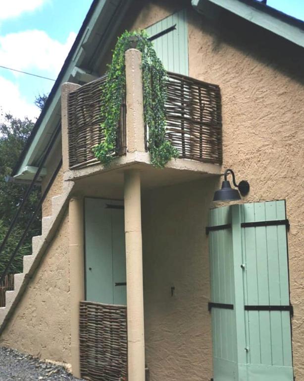 une maison avec une porte verte et un balcon dans l'établissement LA MIELLERIE MAISON ENTIERE 10 pers ISSOR, à Arette