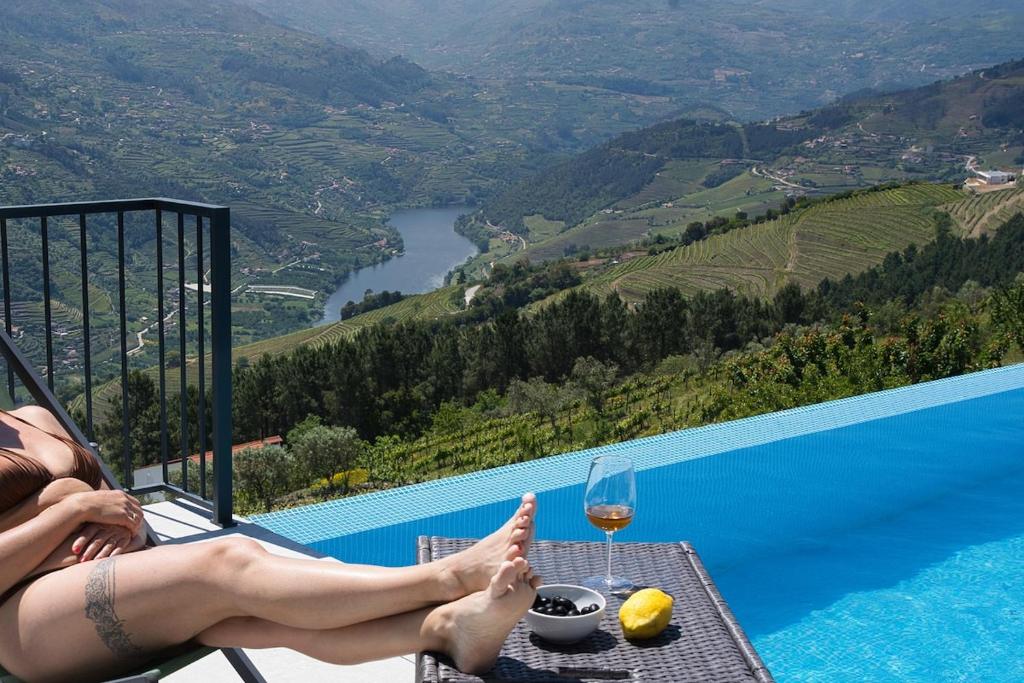 Eine Frau, die auf einem Tisch mit einem Glas Wein sitzt. in der Unterkunft Casa PoliDouro - Vila Marim in Vila Marim