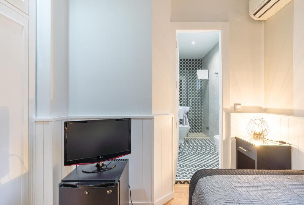 a bedroom with a flat screen tv and a bathroom at BYPILLOW California in Málaga