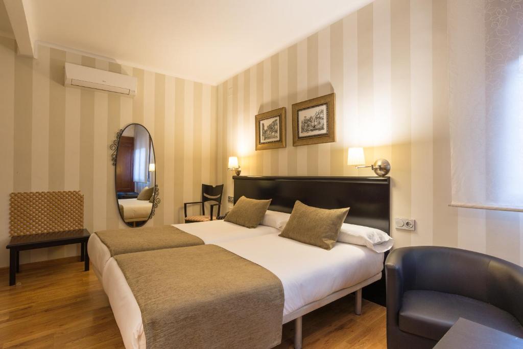 a bedroom with a bed and a chair and a mirror at BYPILLOW California in Málaga