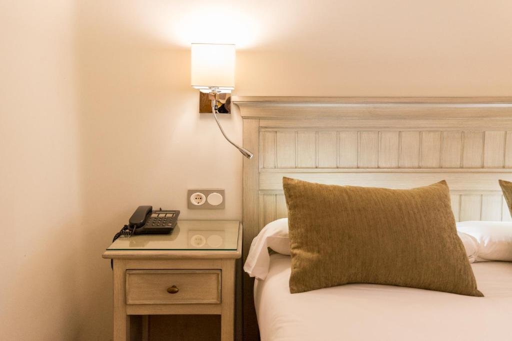 a hotel room with a bed with a lamp and a phone at BYPILLOW California in Málaga