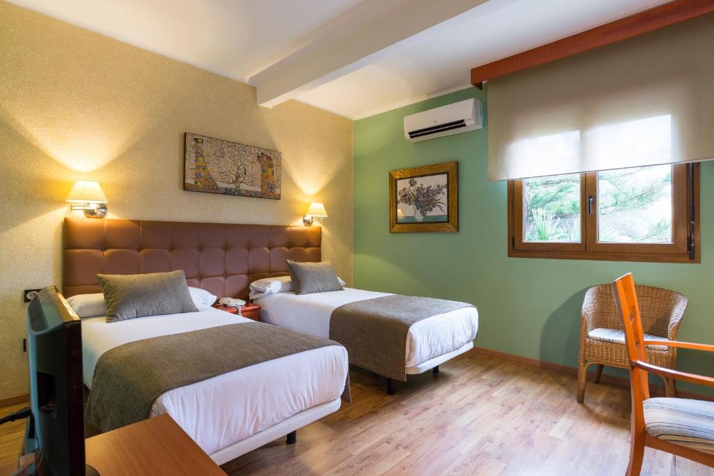 a hotel room with two beds and a chair at BYPILLOW California in Málaga