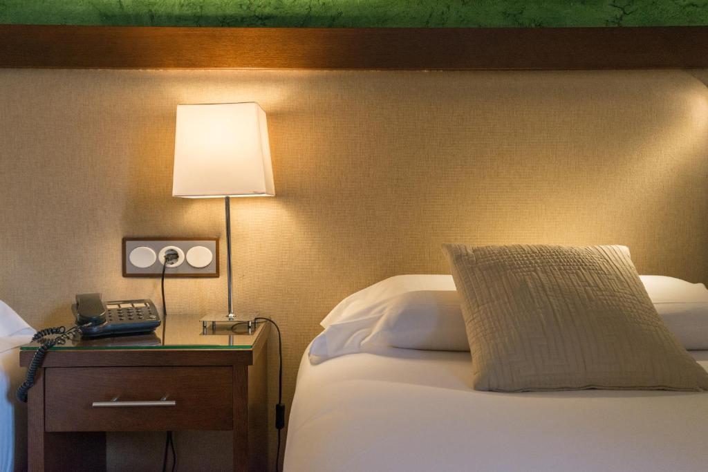 a hotel room with a bed with a lamp and a phone at BYPILLOW California in Málaga