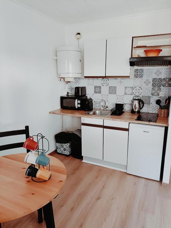 une cuisine avec des armoires blanches et une table en bois dans l'établissement Studio avec piscine partagée Presqu'île de Saint-Mandrier-sur-Mer, à Saint-Mandrier-sur-Mer