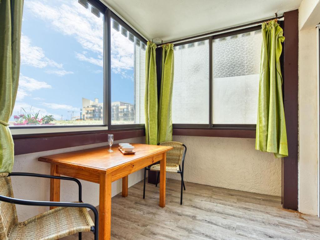 a table and chairs in a room with windows at Apartment Les Terrasses de l'Atlantique-7 by Interhome in Lacanau-Océan