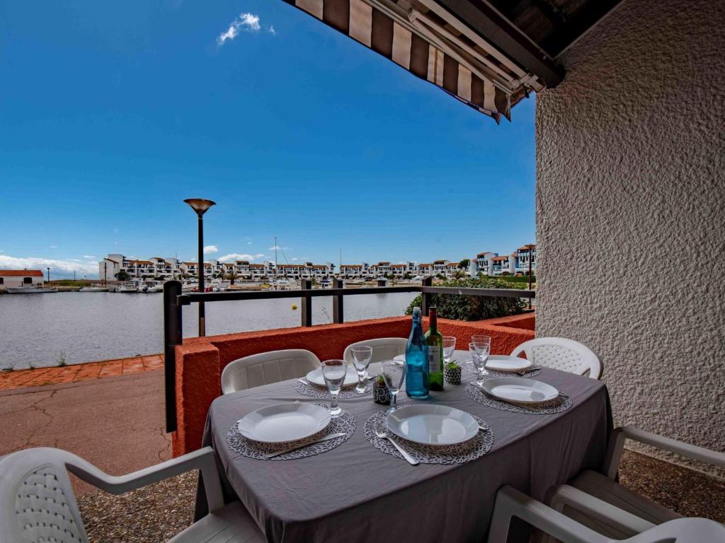 une table avec des assiettes et des verres à vin sur un balcon dans l'établissement Apartment Coudalère-Les Hébrides-3 by Interhome, au Barcarès