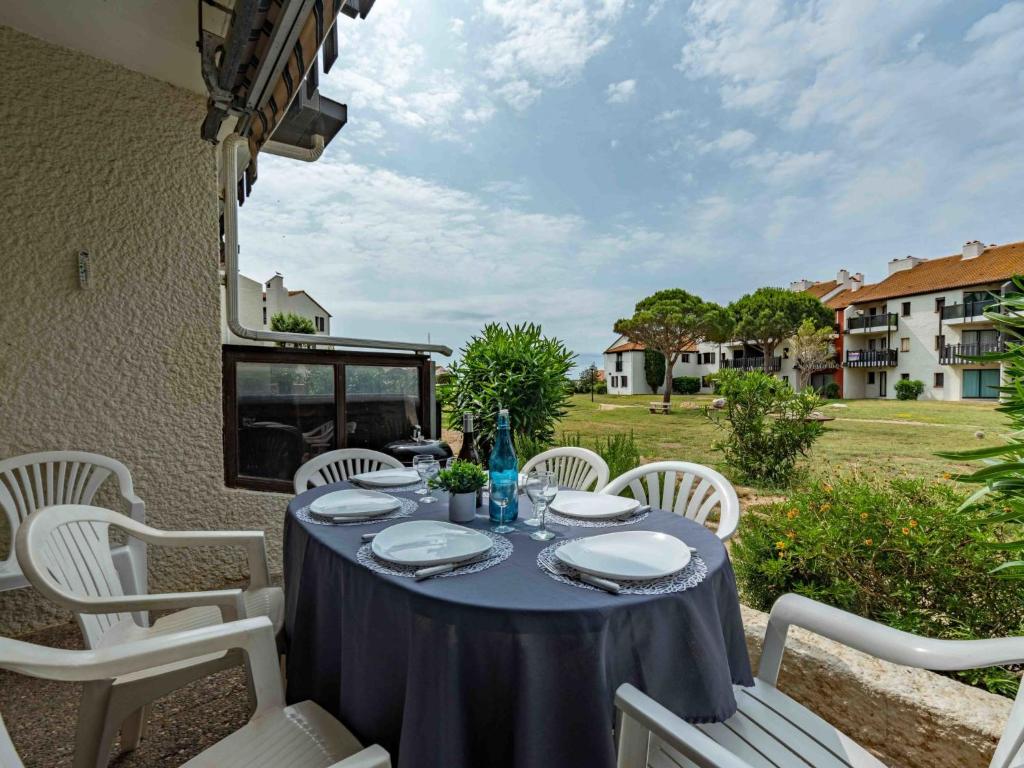 une table avec des chaises blanches et un chiffon de table bleu dans l'établissement Holiday Home Sombrero-4 by Interhome, au Barcarès