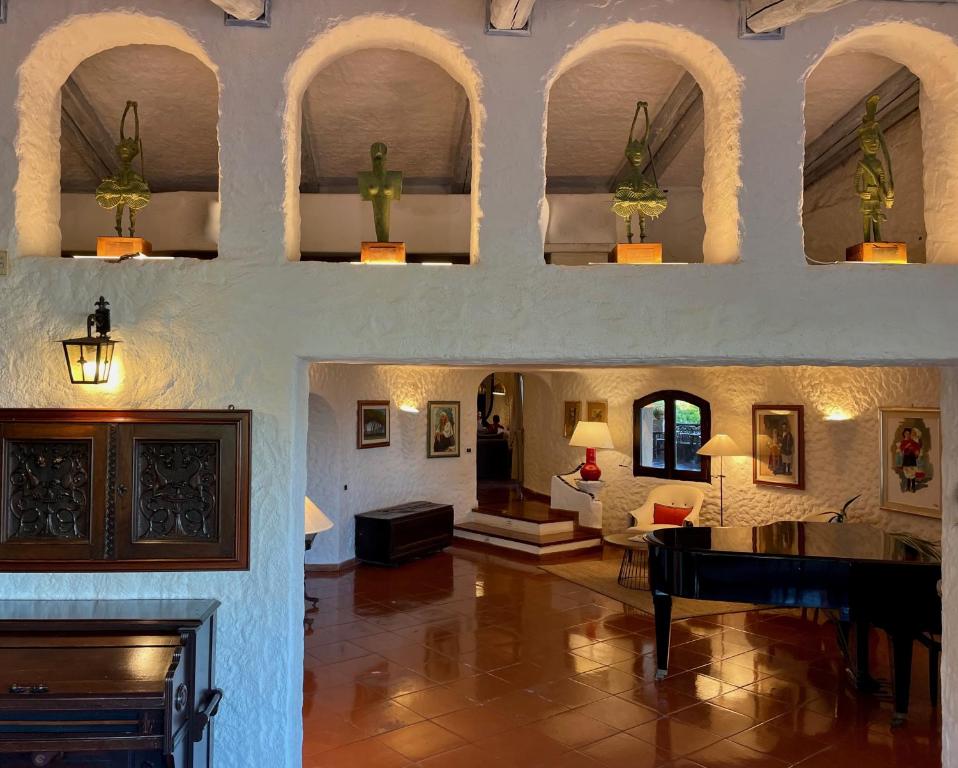 a living room with a piano and a living room with a fireplace at Hotel Don Diego in Porto San Paolo