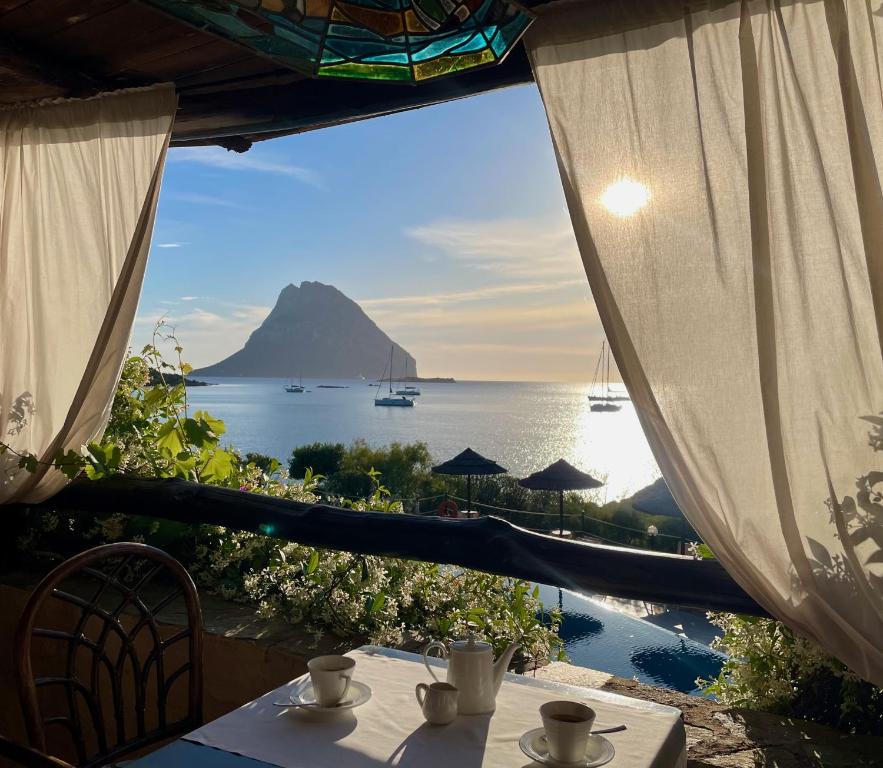 a table with a view of the ocean and a mountain at Hotel Don Diego in Porto San Paolo