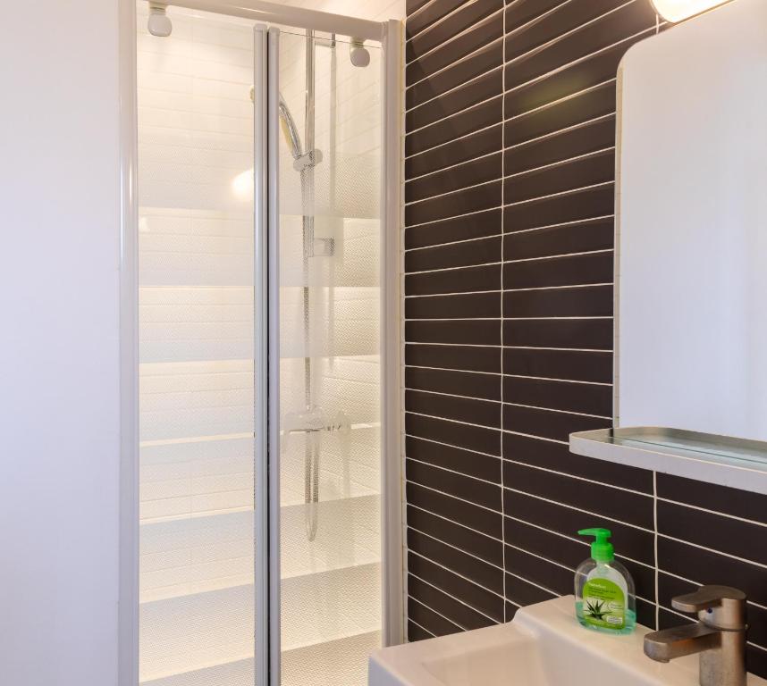 La salle de bains est pourvue d'une douche et d'un lavabo blanc. dans l'établissement Pied-a-terre near Bastille & Voltaire Paris 11th, à Paris