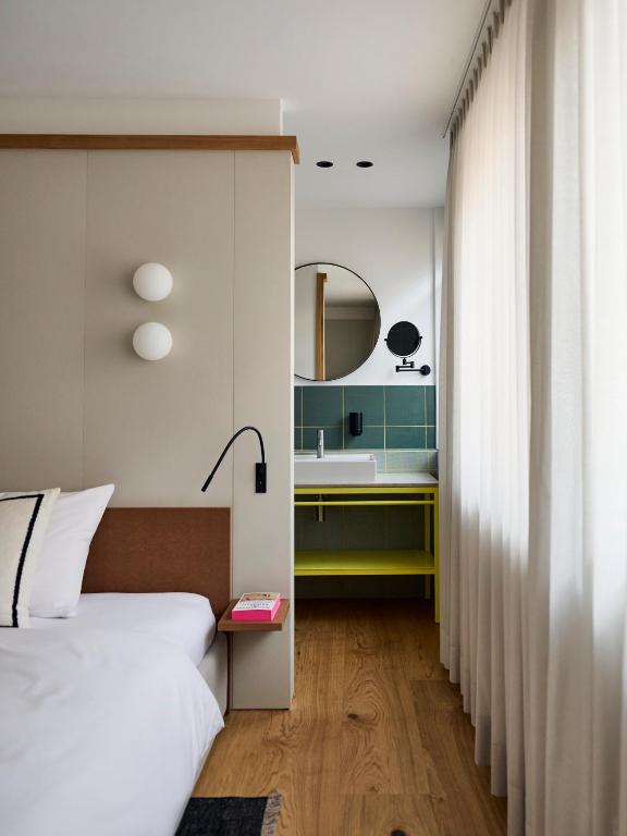 アーレンにあるLUIS Boutique Hotelのベッドと洗面台と鏡のある寝室