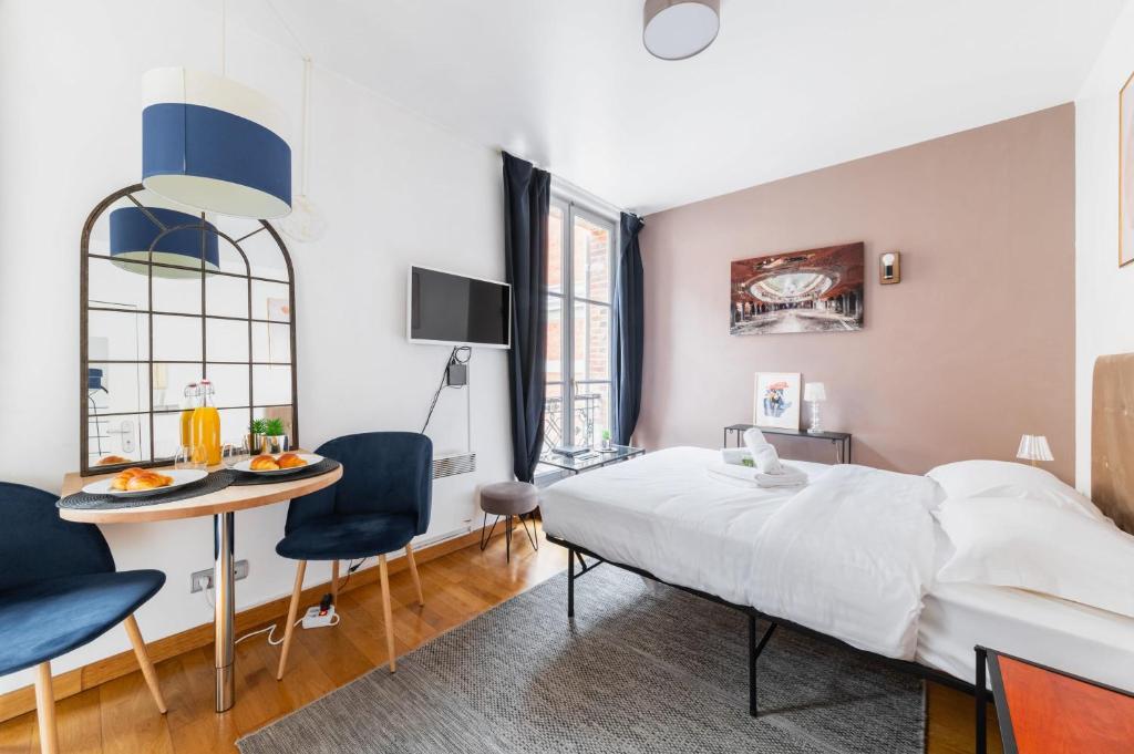 une chambre avec un lit, une table et des chaises dans l'établissement 205 - studio cosy vue sur le musee - Paris 5 - FLAT-GUEST, à Paris