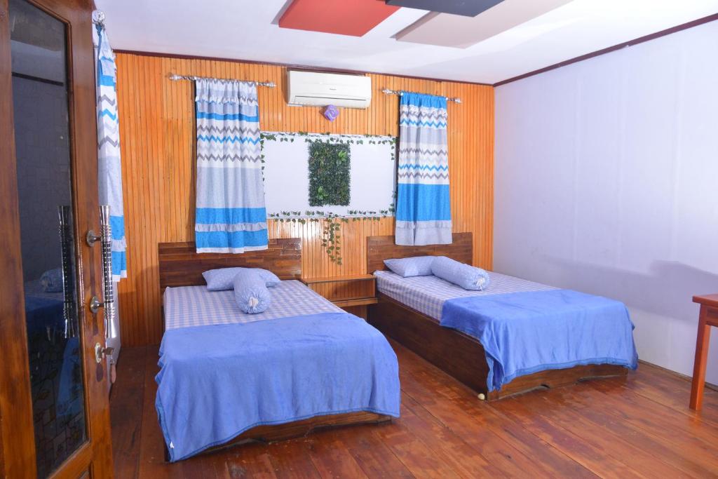 a bedroom with two beds and a window with curtains at Homestay 88 in Dondo