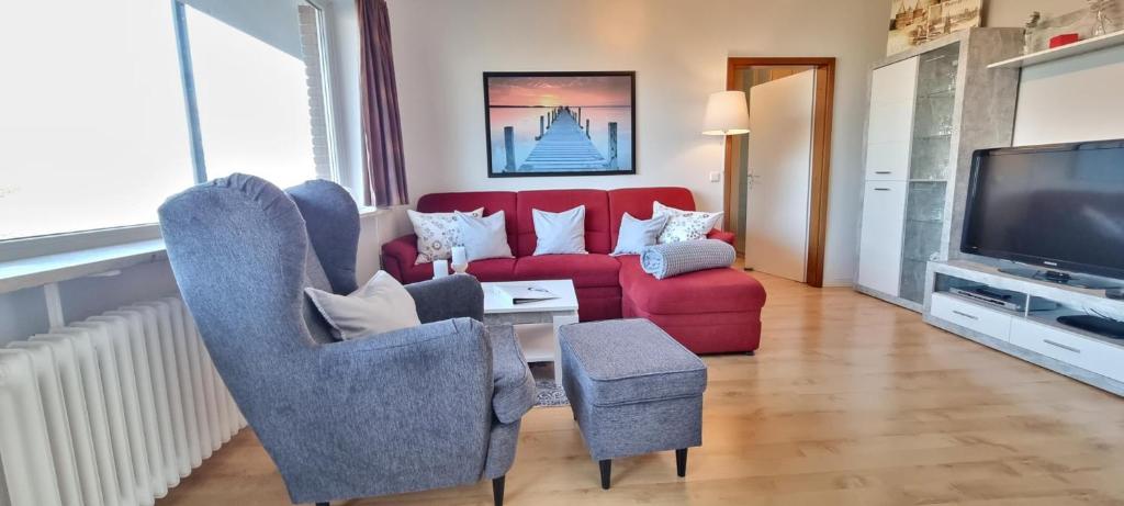 een woonkamer met een rode bank en stoelen bij Stadtdomizil am Binnensee, Haus Bellevue in Heiligenhafen