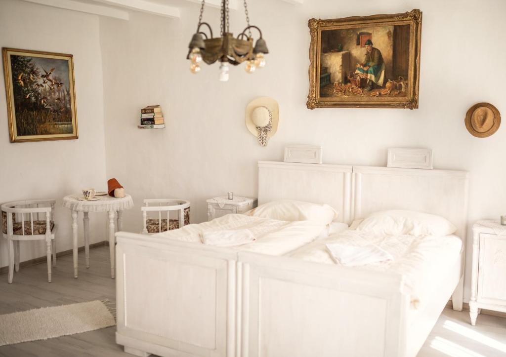 a bedroom with white furniture and a painting on the wall at Pista bácsi háza in Pusztaföldvár