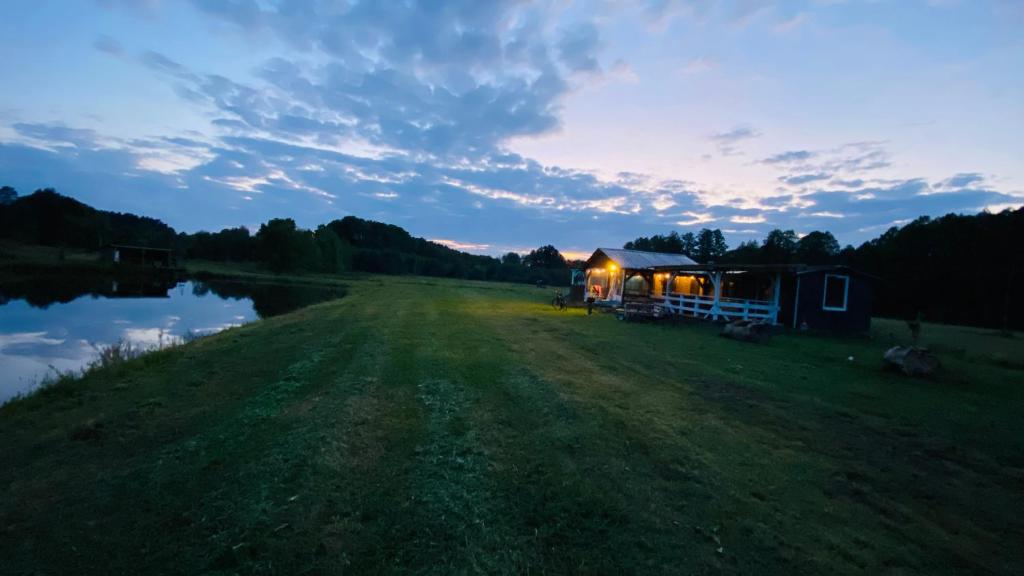 a cabin on a field next to a body of water at Domek Nad Stawem in Miedzichowo