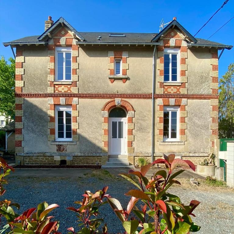 une grande maison en briques avec une porte blanche dans l'établissement Les Lotus de BELLE-YLE, à Yvré-lʼÉvêque